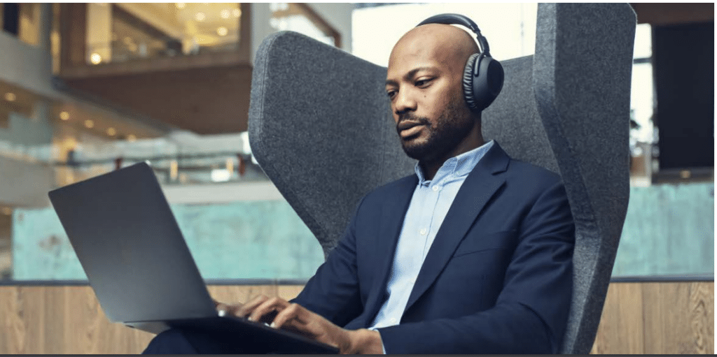 Một người đàn ông đeo tai nghe thuộc epos adapt 600 series làm việc với máy tính