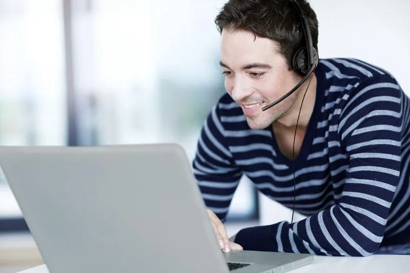 một người đàn ông đeo tai nghe điện thoại viên chống ồn Plantronics c310 làm việc với laptop